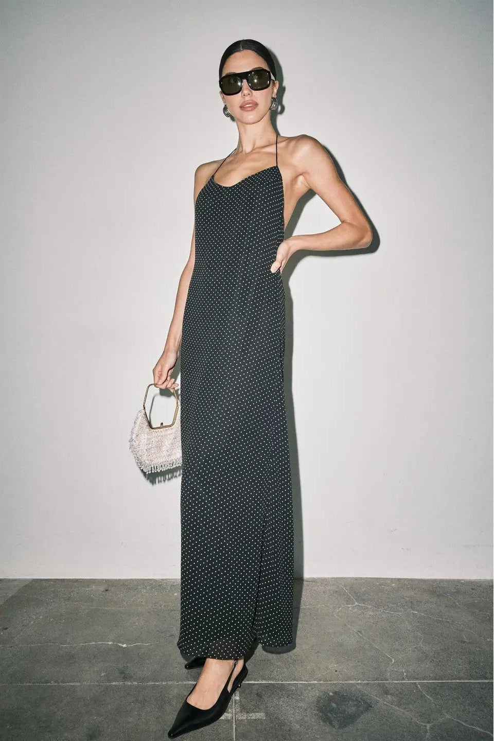 long black halter maxi dress with a small white polka dot pattern and open back