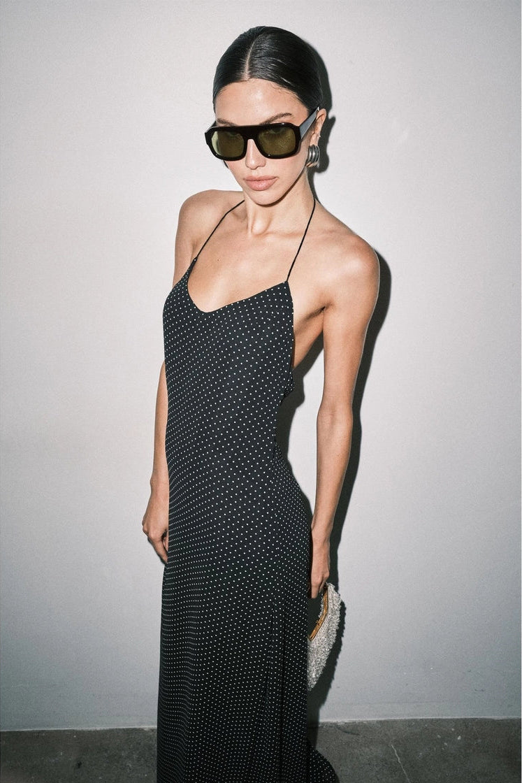 long black halter maxi dress with a small white polka dot pattern and open back